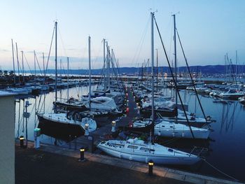 Boats moored at harbor against clear sky