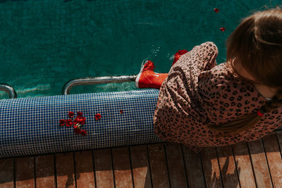 High angle view of woman sitting by swimming pool