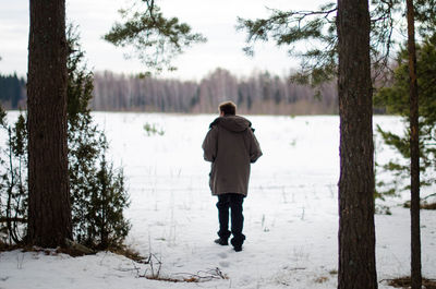 Rear view of woman standing on tree trunk