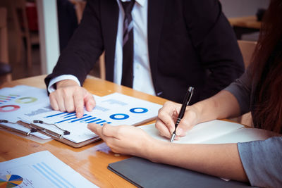 Low section of man holding paper at table