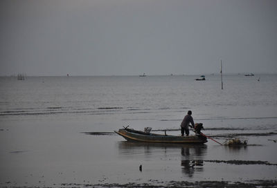 Men fishing in sea against clear sky