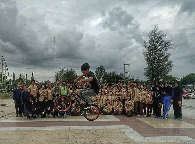 sky, lifestyles, cloud - sky, leisure activity, full length, bicycle, transportation, casual clothing, cloudy, men, mode of transport, tree, water, cloud, land vehicle, person, street, standing