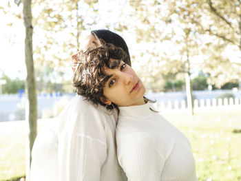 Lesbian couple leaning on each other at autumn park