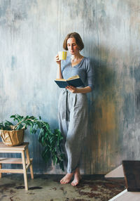 Full length of a young woman standing against wall