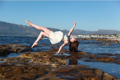 Full length of young woman levitating at beach