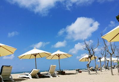 Deck chairs on beach against sky