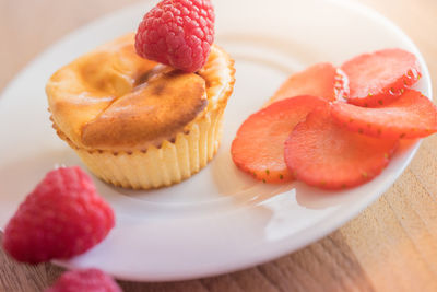 Close-up of cupcake with fruit slices and raspberries on table