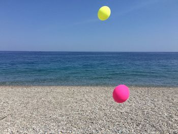 Balloons on beach against blue sky