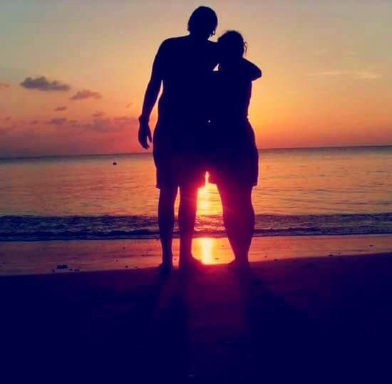 REAR VIEW OF TWO MEN STANDING ON BEACH