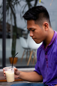 Young man drinking glass on table