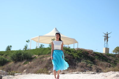 Young woman standing against clear sky at beach