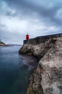 Lighthouse by sea against sky