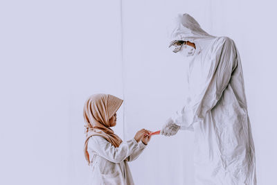 Side view of two women standing against white background