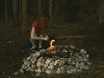 Woman with fire on log in forest