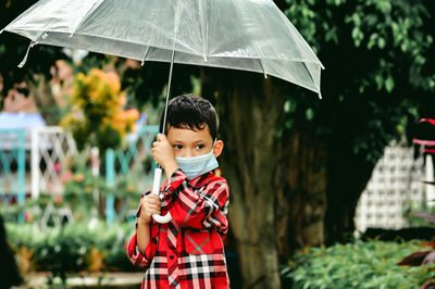 Portrait of boy standing in rain during rainy season