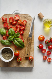 Fresh summer tomatoes, leaves of green basil, on cutting board. top view.