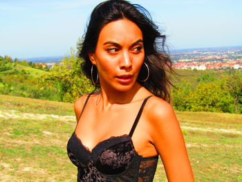 Portrait of beautiful young woman standing on land against sky