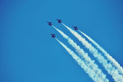 Low angle view of airplane flying against blue sky