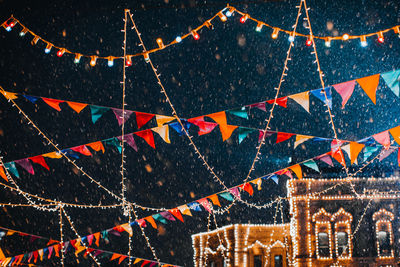 Flying snow in the evening light in festive magic new year atmosphere with garlands and flags