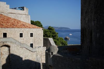 Built structure by sea against blue sky
