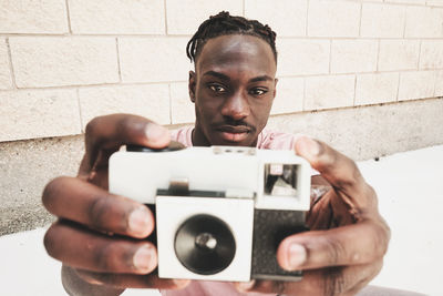 Man taking selfie with camera against wall