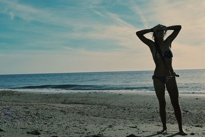 Woman standing on beach against sky during sunset