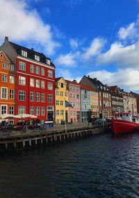 Buildings at waterfront against cloudy sky