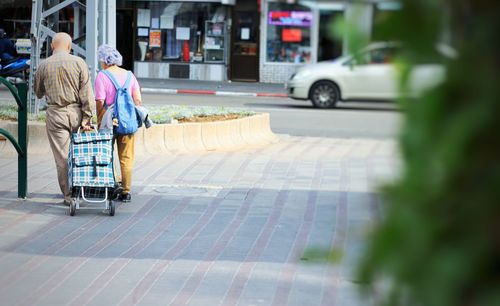 Rear view of people walking on street in city