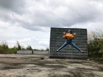 Man jumping on field against sky