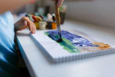 Midsection of boy painting at home