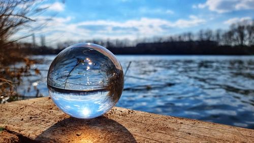 Close-up of crystal ball against sky