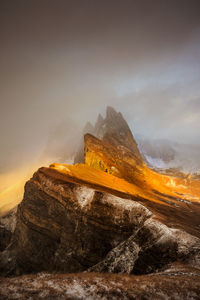 Rock formation on mountain against cloudy sky