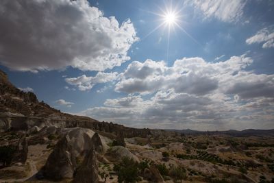 Scenic view of cappadocia against cloudy sky on sunny day