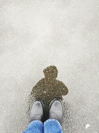 Low section of man standing on snow covered beach