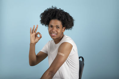 Portrait of smiling young woman standing against blue background