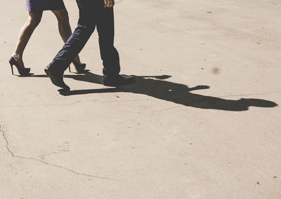 Low section of people walking on concrete