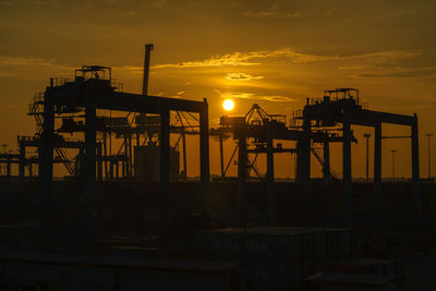 Silhouette cranes against sky during sunset