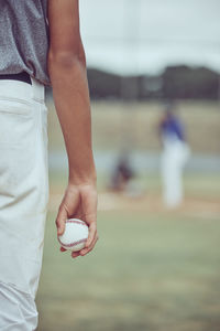 Midsection of man holding baseball