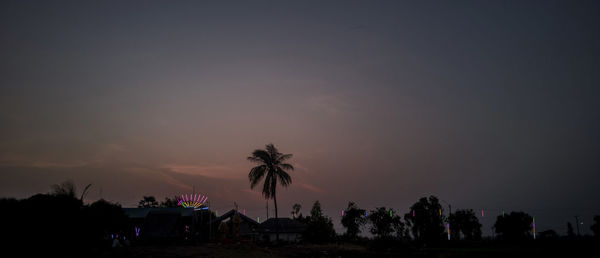 Silhouette people by palm trees against sky during sunset