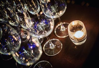 Close-up of wineglasses by illuminated candle on table