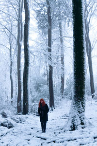 Rear view of woman walking on snow covered landscape