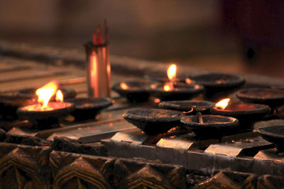 Lit tea light candles in temple against building