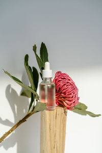 The serum and the flower stand on a piece of wood.