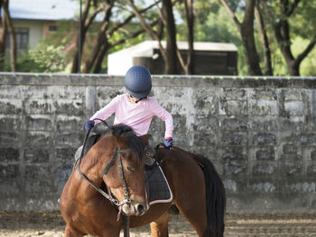 Asian school kid riding or practicing horse at horse ranch.