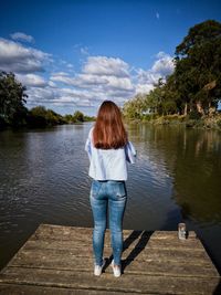 Rear view of man standing on lake against sky