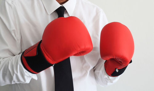 Midsection of man with red umbrella against white background