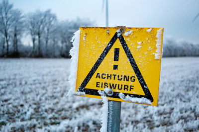 Close-up of yellow sign on snow covered field