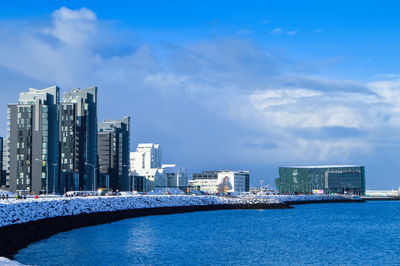 City at waterfront against cloudy sky