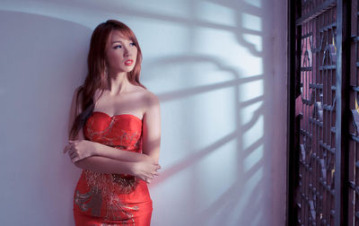 Portrait of beautiful young woman standing against wall