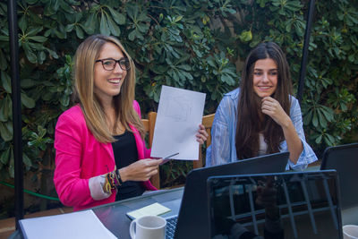 Smiling colleagues discussing over diagram against plants